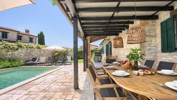 A covered outdoor dining area with a pool, stone walls, and a stone building in the background. - Villa Silene - Authentic villa near Višnjan (Barat)