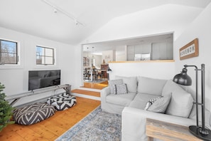 A modern living room with a grey sofa, wooden flooring, and a TV mounted on the wall. - Vermont Farmhouse Escape Near Okemo (Ludlow)