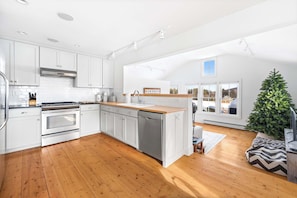A modern kitchen with white cabinets, stainless steel appliances, and a wooden floor. - Vermont Farmhouse Escape Near Okemo (Ludlow)