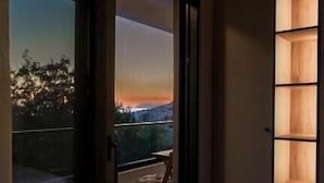 Une chambre dotée d’une porte-fenêtre coulissante donnant sur un balcon avec vue sur le coucher de soleil.