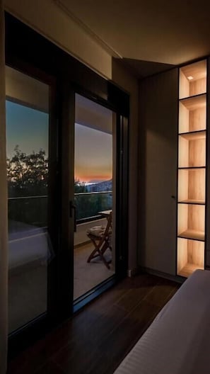A bedroom with a sliding glass door leading to a balcony with a view of the sunset. - Luxury Vila with Pool (Bar)