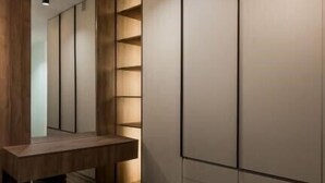 Une salle de bain moderne avec un meuble-lavabo en bois, un miroir et un grand dressing avec des portes coulissantes.