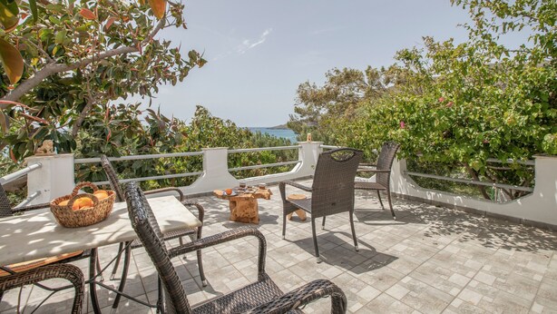 An outdoor patio with wicker furniture, a table, and a basket of oranges. - Entire Cottage in Kerames, Crete – 250 m from the Beach (Agiou Vasileiou)