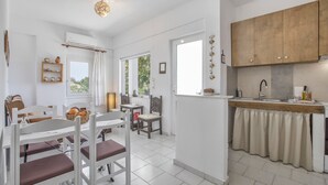 A modern kitchen with white cabinetry, a built-in oven, and a window overlooking greenery. - Entire Cottage in Kerames, Crete – 250 m from the Beach (Agiou Vasileiou)