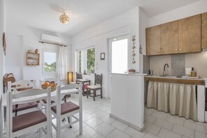 A modern kitchen with white cabinetry, a built-in oven, and a window overlooking greenery. - Entire Cottage in Kerames, Crete – 250 m from the Beach (Agiou Vasileiou)