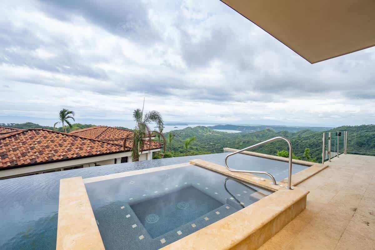Ein Pool im Infinity-Stil mit Blick auf eine gebirgige Landschaft und einen bewölkten Himmel.