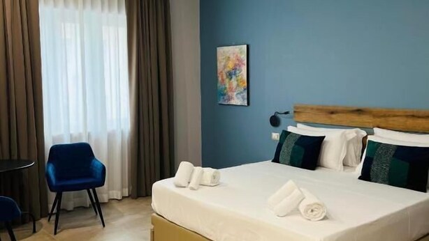 Ein Hotelzimmer mit Bett, Stuhl und einem Bild an der Wand.