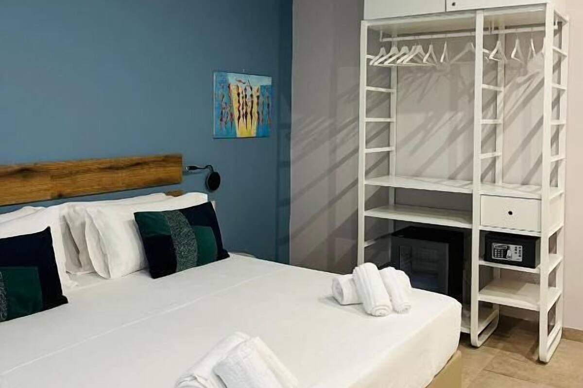 A bedroom with a bed, a wardrobe, and a painting on the wall.