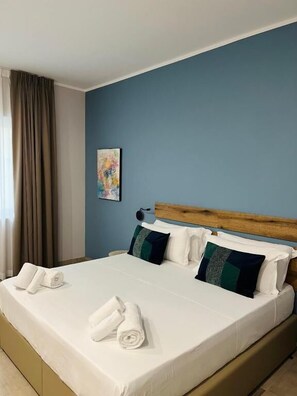 Une chambre d’hôtel avec un grand lit, une tête de lit en bois et un mur bleu.
