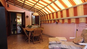 Ein Essbereich mit Tisch und Stühlen, einer gepolsterten Bank und einer Decke mit Stoffstreifen.