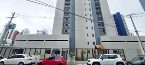Ein mehrstöckiges Gebäude mit modernem architektonischen Design, das durch ein markantes vertikales Element und eine Reihe von Balkonen gekennzeichnet ist.