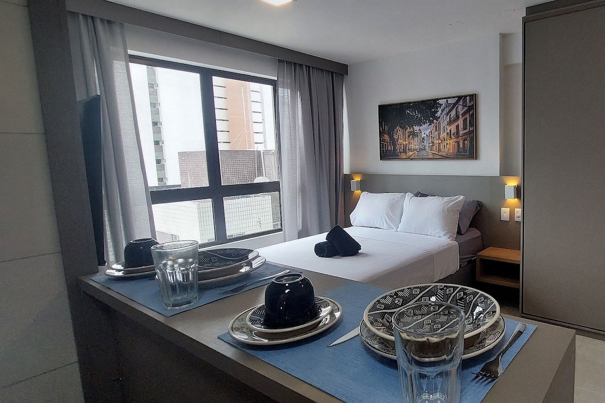 Une chambre d’hôtel avec un lit, une table de chevet, une fenêtre avec des rideaux, un tableau et un miroir.