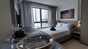 Une chambre d’hôtel avec un lit, une table avec un plateau préparé, une fenêtre avec des rideaux et un tableau au mur.