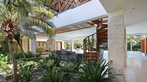 A modern outdoor area with a spiral staircase, seating, and lush greenery. - Villa Monica: Private retreat near golf w/ staff, pool & golf cart (Punta Cana)