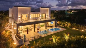 Une maison moderne à deux étages, dotée d’une piscine, d’un espace extérieur aménagé et offrant une vue sur le paysage.