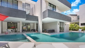 Un edificio moderno con piscina, area relax all'aperto e zona coperta.