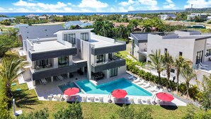 A modern multi-story house with a swimming pool, outdoor seating, and a view of the ocean. - Las Palmas 3: Luxury retreat w/ pool, Jacuzzi, games, golf carts & full staff (Punta Cana)