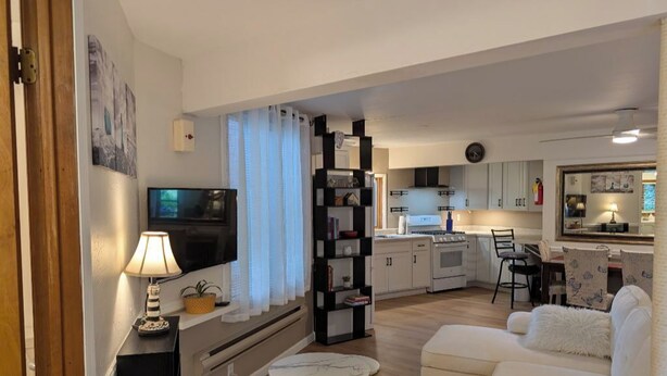 Una sala de estar moderna con un sofá blanco, un televisor, una lámpara y una estantería.