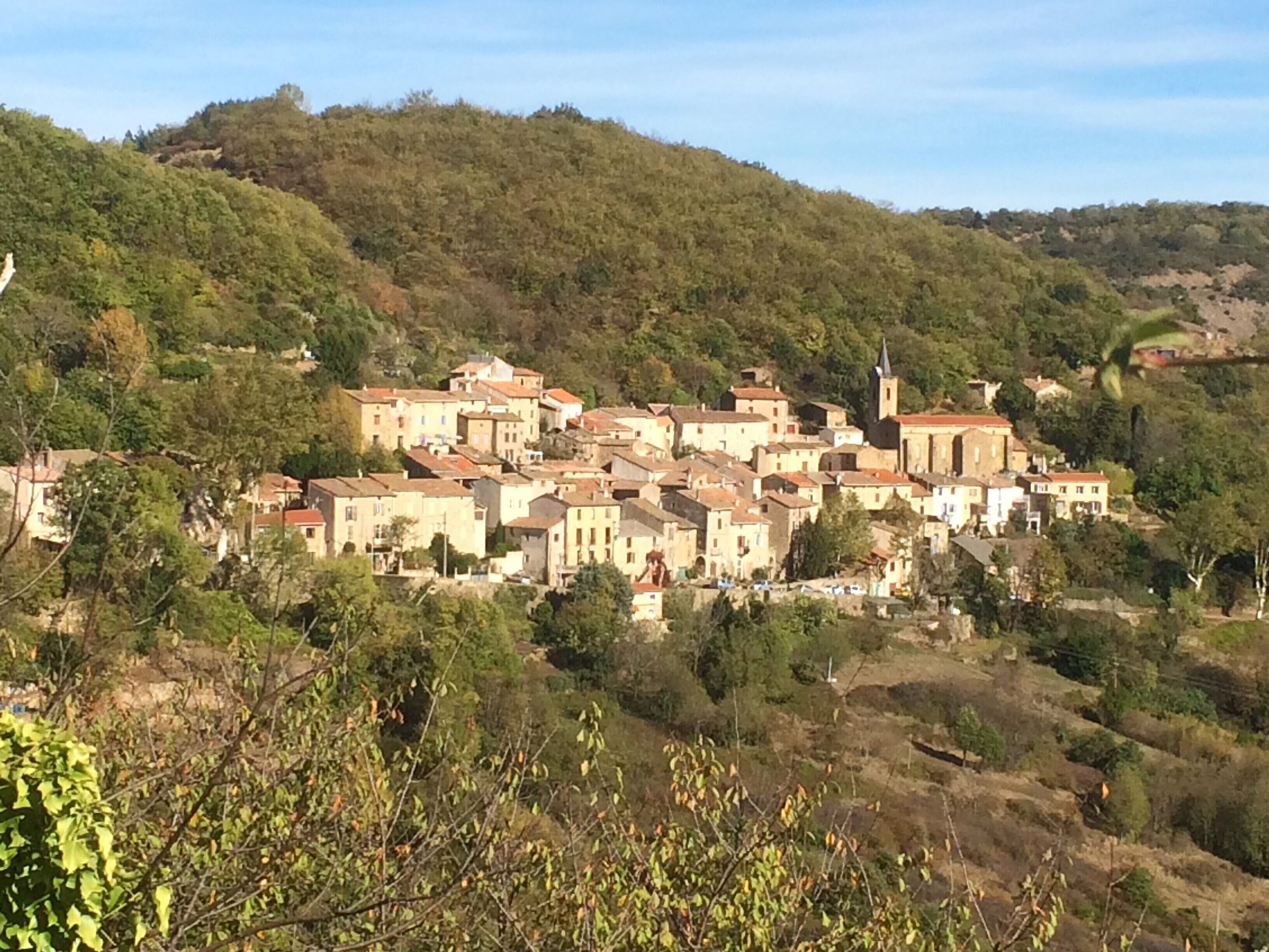 A hillside village with traditional buildings, a church, and a hilltop view.