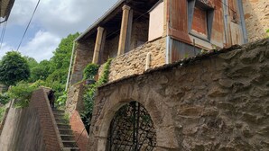 A rustic stone building with a balcony, a staircase, and a metal gate. - Fine vacation home in mountain village; endless hiking, cycling and MTB possibilities (Saint-Gervais-sur-Mare)
