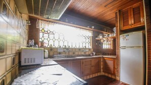 Una cocina con armarios de madera, un refrigerador y una ventana con diseño hexagonal.