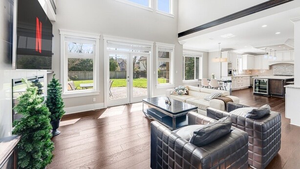 A spacious living area with a large window, a fireplace, and a modern kitchen in the background. - Sunnymede Vacation Stay (Richmond)