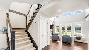 A spacious living area with a staircase, a white door, and a view of the outdoors. - Sunnymede Vacation Stay (Richmond)