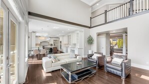 A spacious living area with a modern design, featuring a large coffee table, sofas, and a staircase leading to an upper level. - Sunnymede Vacation Stay (Richmond)
