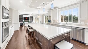 A modern kitchen with a large island, stainless steel appliances, and pendant lighting. - Sunnymede Vacation Stay (Richmond)