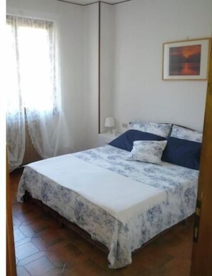 Une chambre à coucher avec un lit, une table de chevet, une lampe et un tableau au mur.
