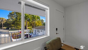 Ein Zimmer mit großem Fenster, einer Tür und einer Bank.