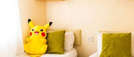 A room with two beds, each with a pillow and a Pikachu plush toy.
