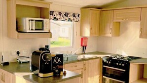 A compact kitchen with a microwave, toaster, and stove. - North Wales Coastal Stay 2 (Rhyl)