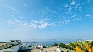 Una terrazza sul tetto con diverse unità di condizionamento, vista libera sul mare e skyline urbano in lontananza.