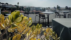 Una terrazza sul tetto con tavoli e sedie, affacciata su un panorama cittadino.
