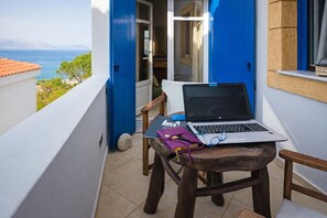 Un balcon avec un ordinateur portable, un carnet et un stylo posés sur un tabouret en bois, offrant une vue panoramique.