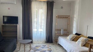 Ett modernt vardagsrum med en soffa, en tv, ett litet bord och ett mönstrat golv.
