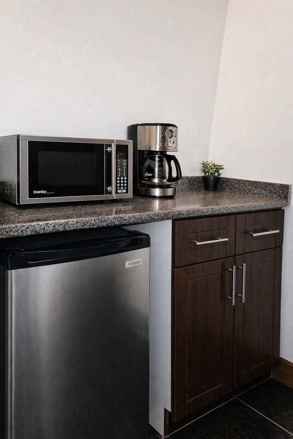 A kitchen with a microwave, coffee maker, dishwasher, and dark wooden cabinets.