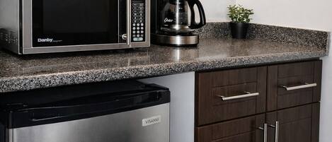 A kitchen with a microwave, coffee maker, dishwasher, and dark wooden cabinets.