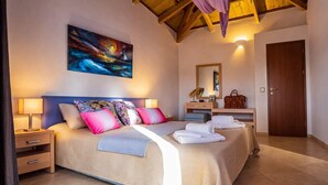 A hotel room with a large bed, bedside lamps, a nightstand, a wooden headboard, a painting on the wall, a mirror, a desk with a lamp, a handbag, and a door.
