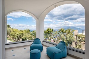 Ein modernes Zimmer mit zwei blauen Sitzsäcken und einem großen Bogenfenster mit Blick auf eine Küstenlandschaft.