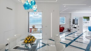 Un salon moderne doté d’une grande fenêtre, d’un coin repas avec une table et des chaises, et d’un canapé rouge.