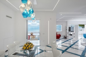 Ein modernes Wohnzimmer mit großem Fenster, einem Essbereich mit Tisch und Stühlen sowie einem roten Sofa.