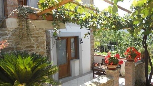 A stone wall, a wooden pergola, a door, and potted plants. - Relaxation, nature and history in the historic village a 5 km from the sea. (Ogliastro Cilento)