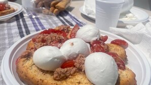 A table with a plate of food, including a pastry with toppings and a scoop of ice cream, set against a backdrop of a body of water and distant land. - Relaxation, nature and history in the historic village a 5 km from the sea. (Ogliastro Cilento)