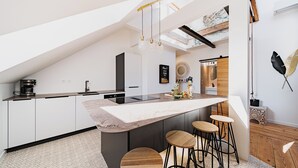 Una cocina moderna con una isla grande, taburetes de bar y una cafetera.