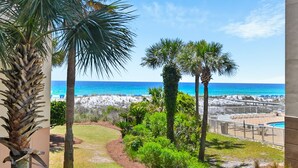 A view of a beach with palm trees, a pool, and a clear blue sky. - 🌊Lazy River | Lagoon Pool + Splash Pad | Walk to Beach | Waterscape 205B⛱️ (Fort Walton Beach)