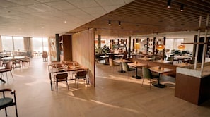 Un restaurant spacieux doté d’un plancher en bois, de plusieurs espaces de restauration et baigné de lumière naturelle grâce à de grandes fenêtres.