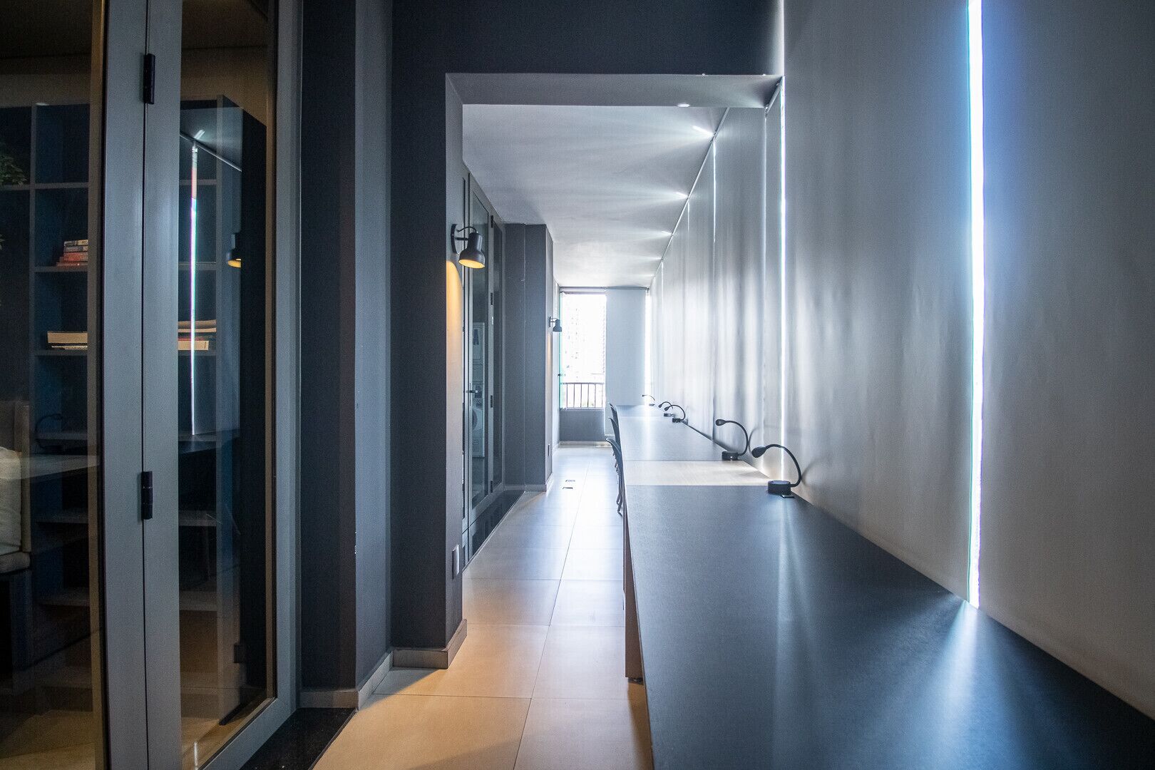 A modern hallway with glass doors, a long table, and a view to the outside.
