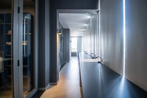 Um corredor moderno com portas de vidro, uma mesa comprida e vista para o exterior.